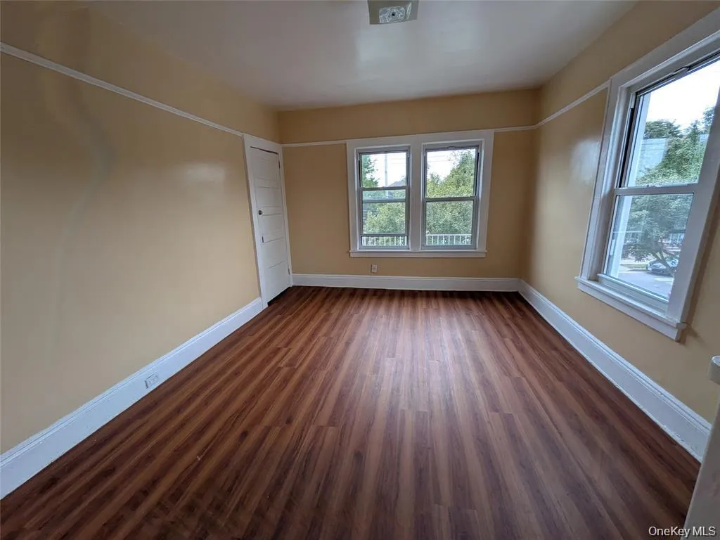Empty room with baseboards and dark wood-style flooring Empty room with baseboards and dark wood-style flooring