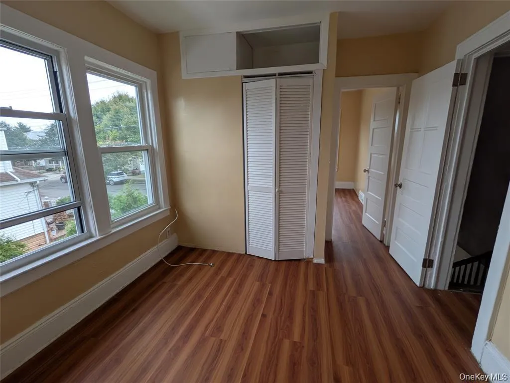 Unfurnished bedroom featuring dark wood-type flooring and a closet Unfurnished bedroom featuring dark wood-type flooring and a closet