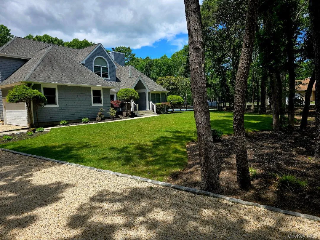 Back of house with a chimney, a shingled roof, a yard, driveway, and an attached garage Back of house with a chimney, a shingled roof, a yard, driveway, and an attached garage