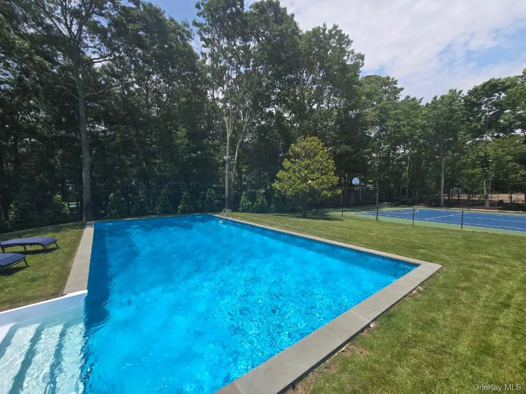 Outdoor pool featuring a patio area and a tennis court Outdoor pool featuring a patio area and a tennis court