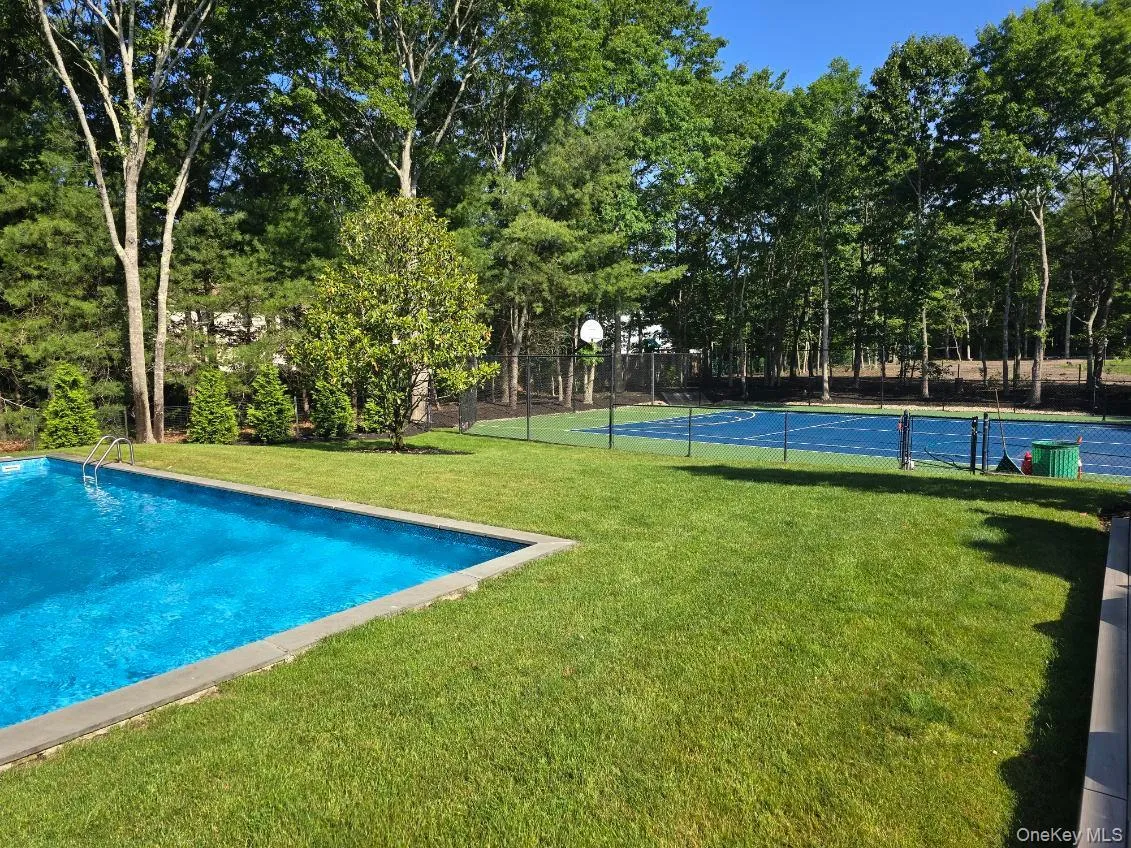 View of swimming pool with community basketball court and view of wooded area View of swimming pool with community basketball court and view of wooded area