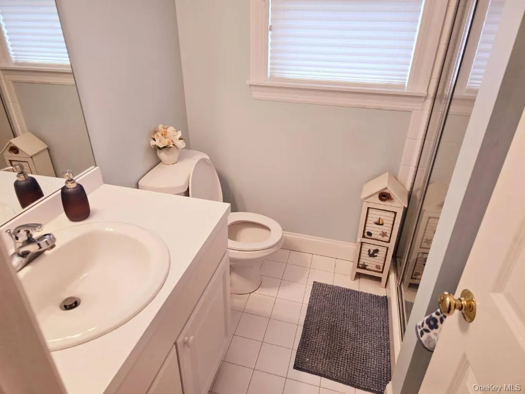 Full bath with a shower stall, vanity, light tile patterned floors, and healthy amount of natural light Full bath with a shower stall, vanity, light tile patterned floors, and healthy amount of natural light