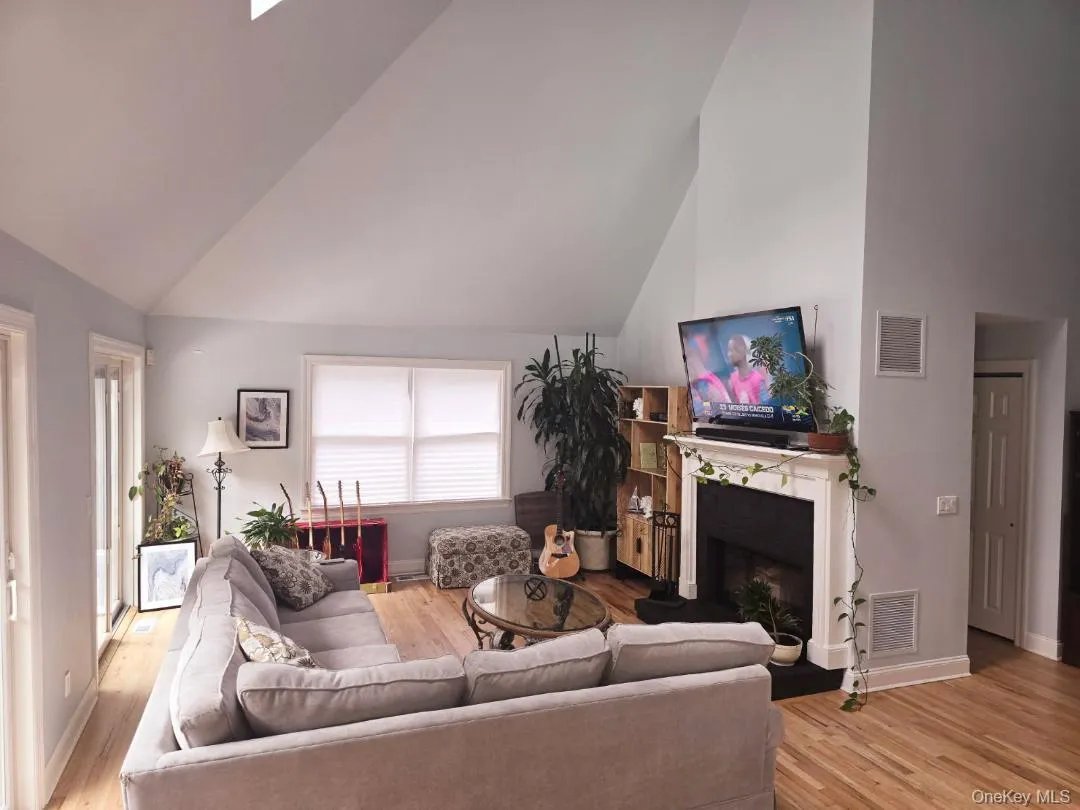 Living room featuring a fireplace, light wood-style flooring, and high vaulted ceiling Living room featuring a fireplace, light wood-style flooring, and high vaulted ceiling