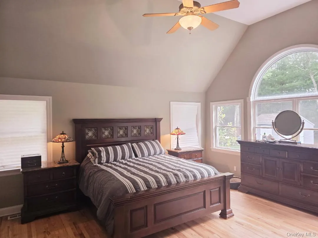 Bedroom with vaulted ceiling, light wood-type flooring, and a ceiling fan Bedroom with vaulted ceiling, light wood-type flooring, and a ceiling fan