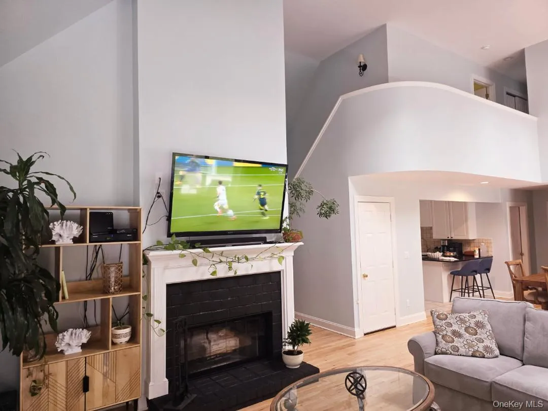 Living area featuring light wood-style flooring, a fireplace, and high vaulted ceiling Living area featuring light wood-style flooring, a fireplace, and high vaulted ceiling