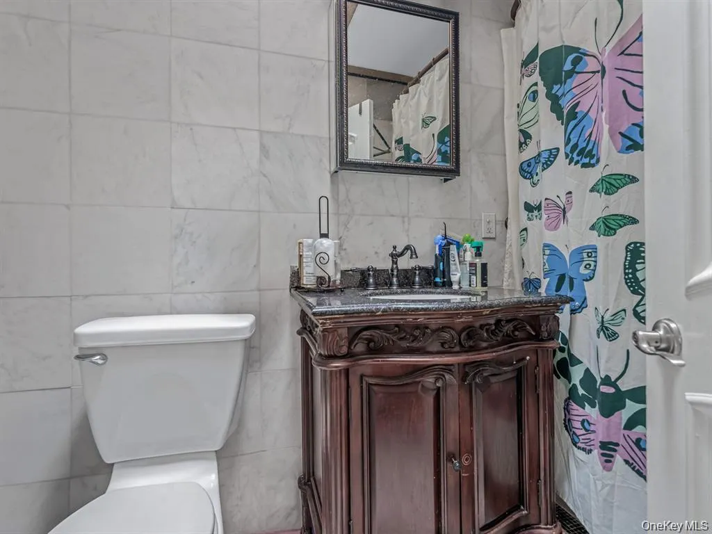 Bathroom featuring tile walls, a shower with curtain, and vanity Bathroom featuring tile walls, a shower with curtain, and vanity