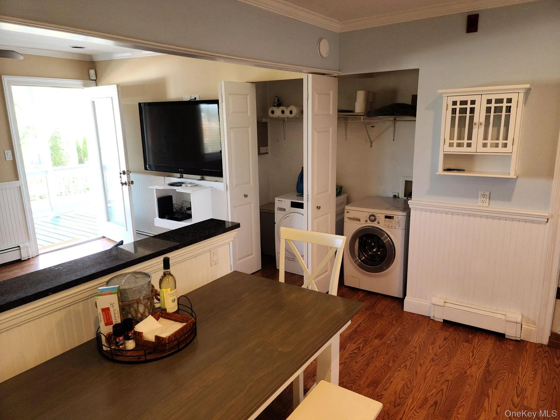 Laundry area with ornamental molding, wainscoting, a baseboard heating unit, dark wood-style flooring, and separate washer and dryer Laundry area with ornamental molding, wainscoting, a baseboard heating unit, dark wood-style flooring, and separate washer and dryer