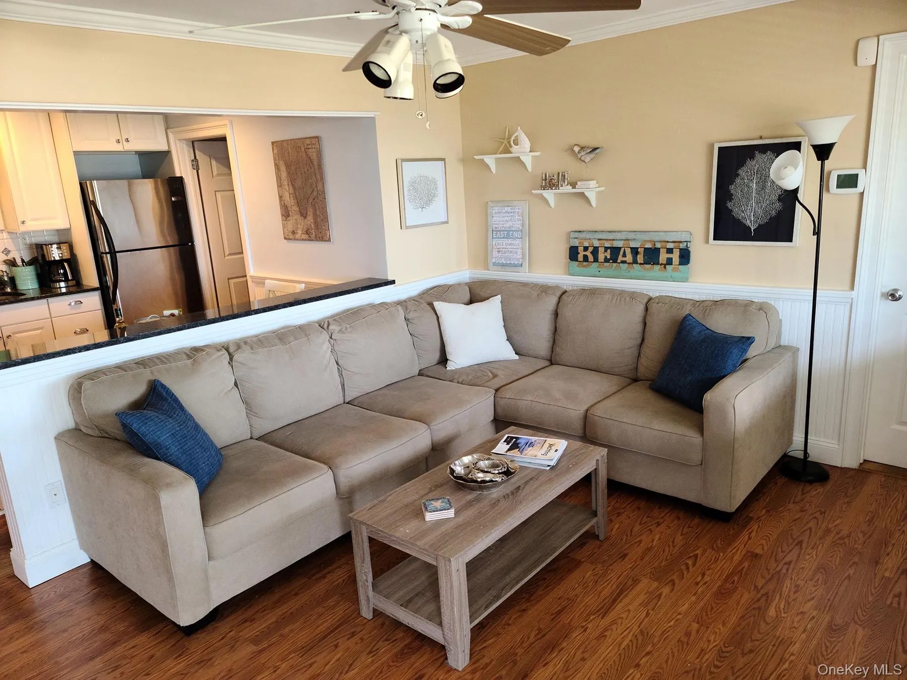 Living room with ornamental molding, wood finished floors, ceiling fan, and a wainscoted wall Living room with ornamental molding, wood finished floors, ceiling fan, and a wainscoted wall