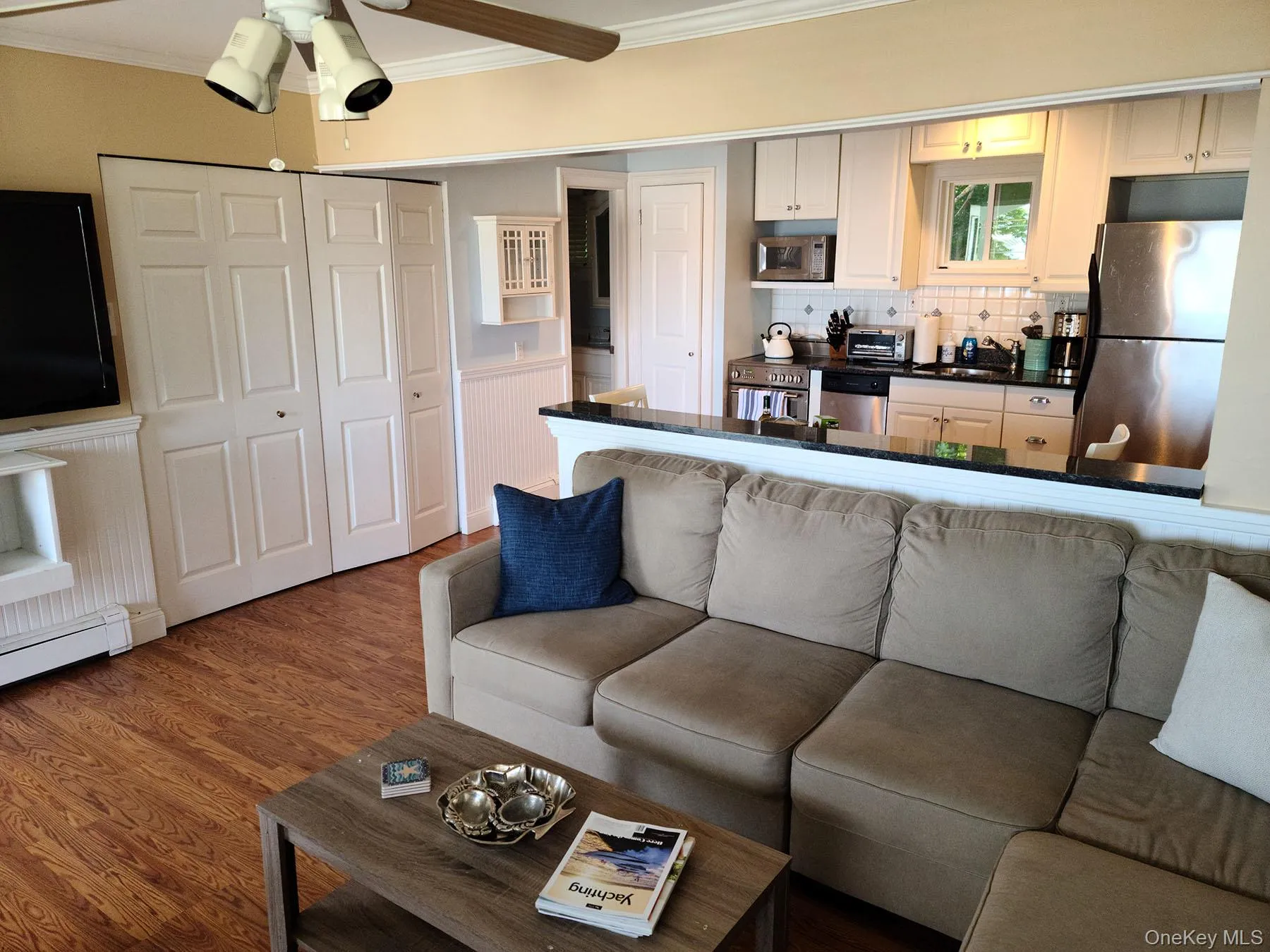 Living room featuring ornamental molding, wood finished floors, ceiling fan, and a wainscoted wall Living room featuring ornamental molding, wood finished floors, ceiling fan, and a wainscoted wall