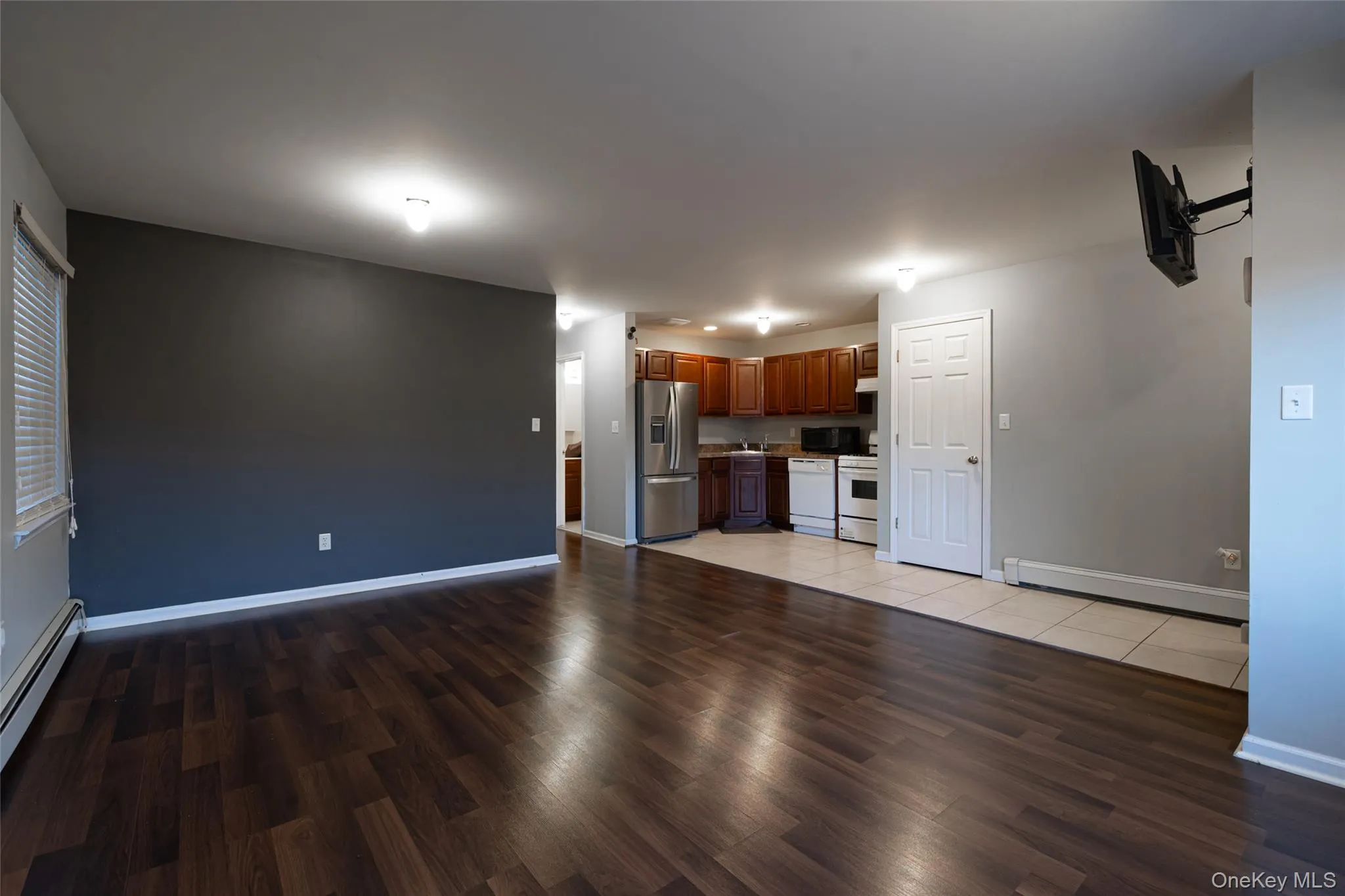 Unfurnished living room featuring light wood-style flooring and baseboard heating Unfurnished living room featuring light wood-style flooring and baseboard heating