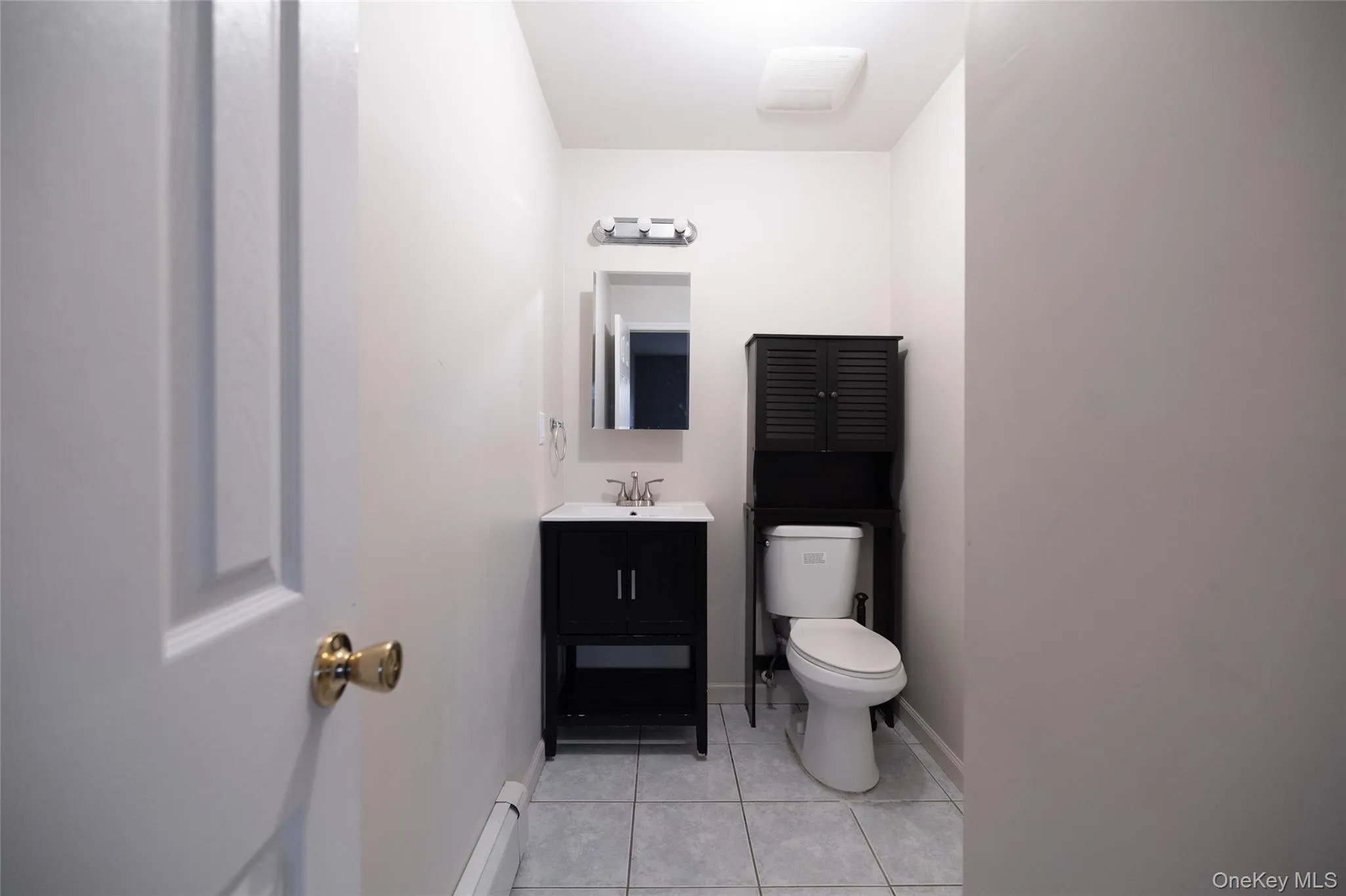 Half bath featuring vanity, a baseboard radiator, and light tile patterned flooring Half bath featuring vanity, a baseboard radiator, and light tile patterned flooring