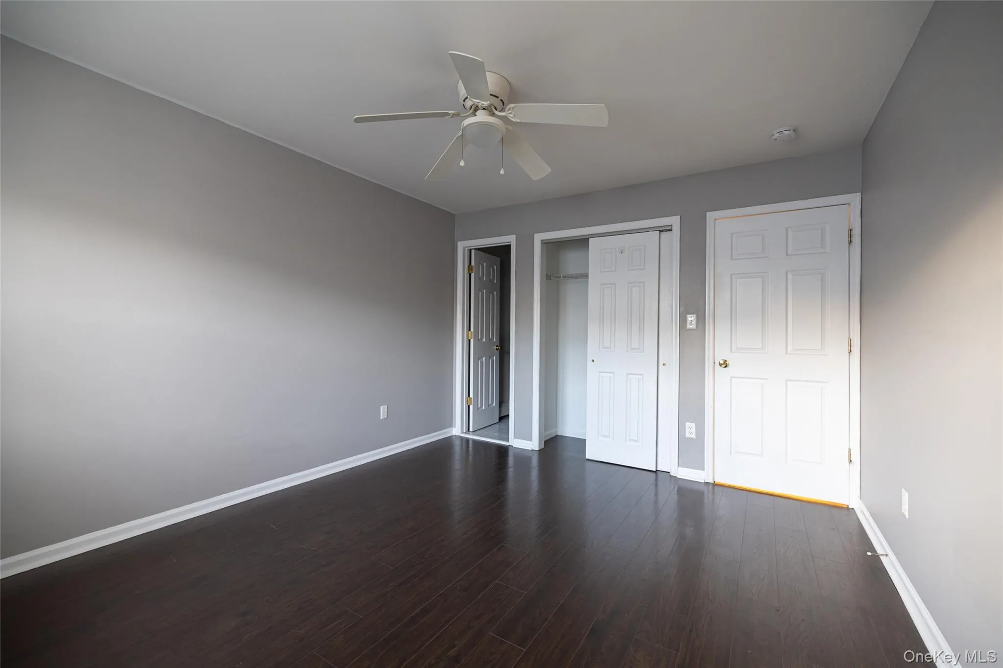 Unfurnished bedroom featuring dark wood-type flooring, a closet, and a ceiling fan Unfurnished bedroom featuring dark wood-type flooring, a closet, and a ceiling fan