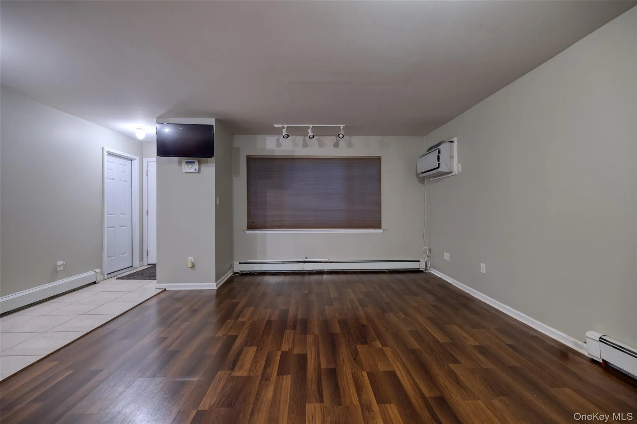 Spare room with dark wood-style floors, baseboard heating, and track lighting Spare room with dark wood-style floors, baseboard heating, and track lighting