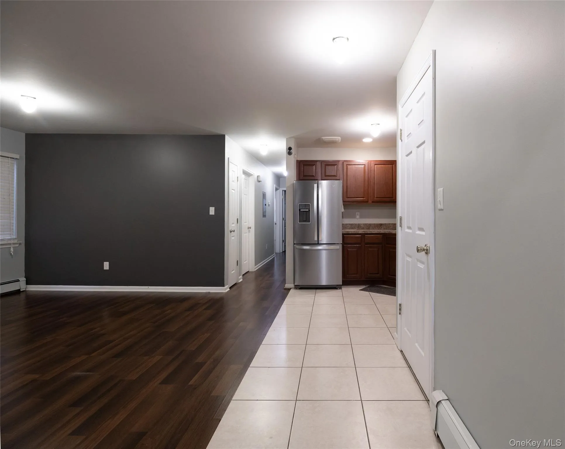 Kitchen featuring stainless steel fridge with ice dispenser, a baseboard radiator, and light wood finished floors Kitchen featuring stainless steel fridge with ice dispenser, a baseboard radiator, and light wood finished floors