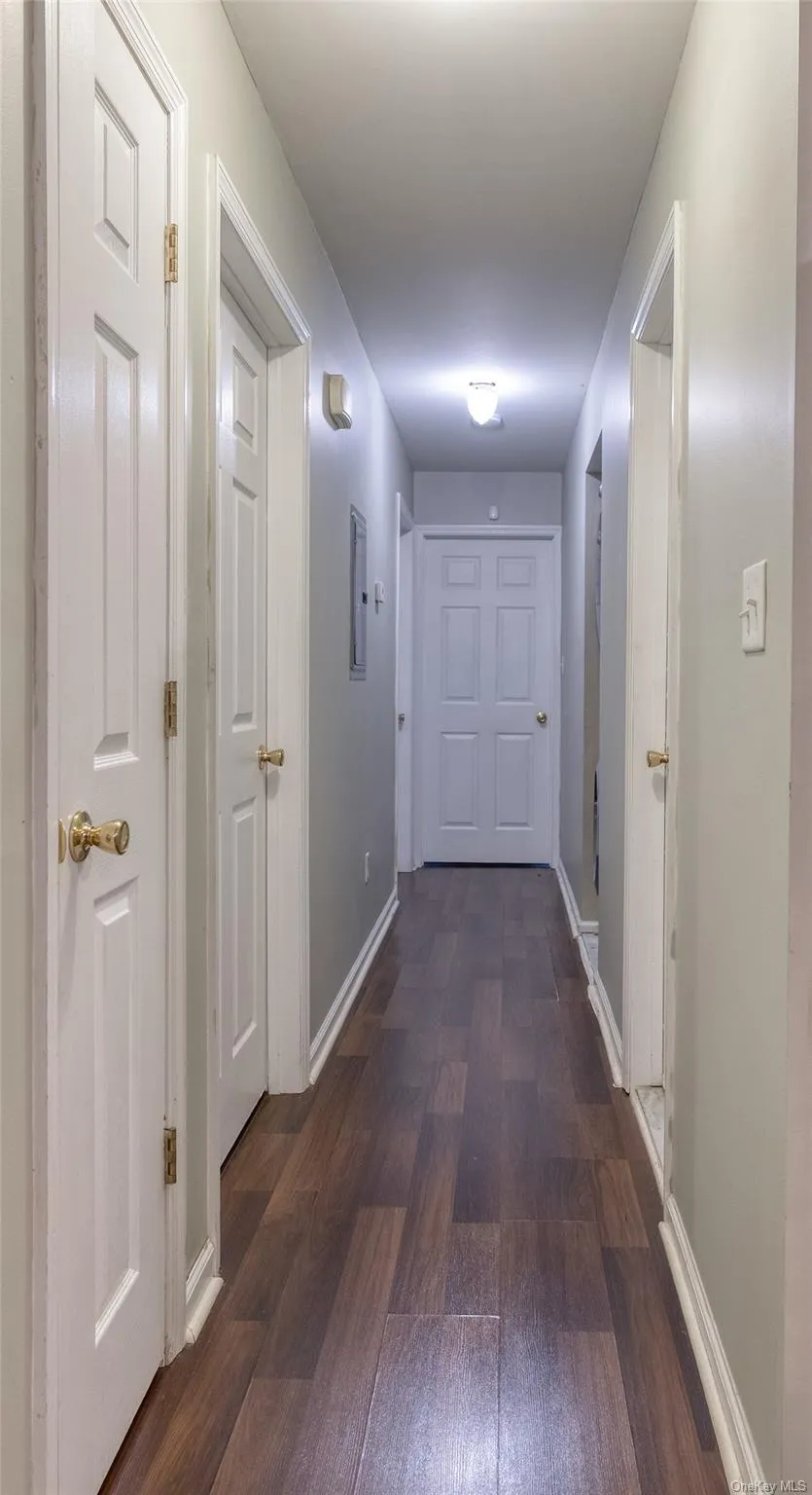 Corridor with dark wood-style floors and baseboards Corridor with dark wood-style floors and baseboards