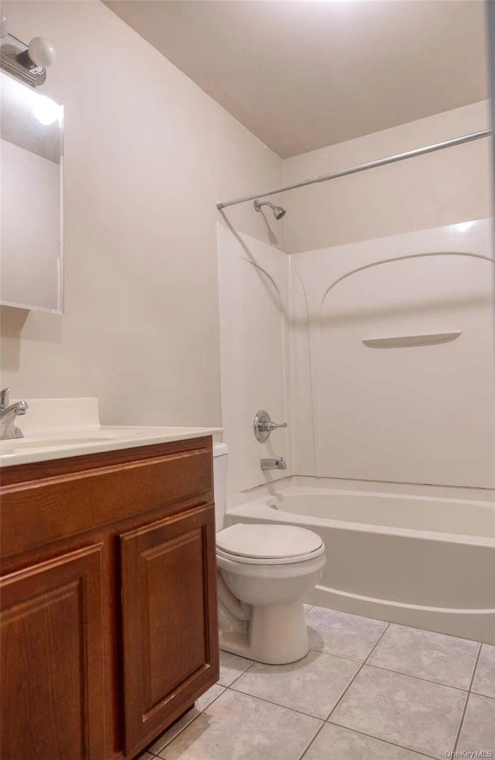 Full bathroom featuring tub / shower combination, vanity, and light tile patterned floors Full bathroom featuring tub / shower combination, vanity, and light tile patterned floors