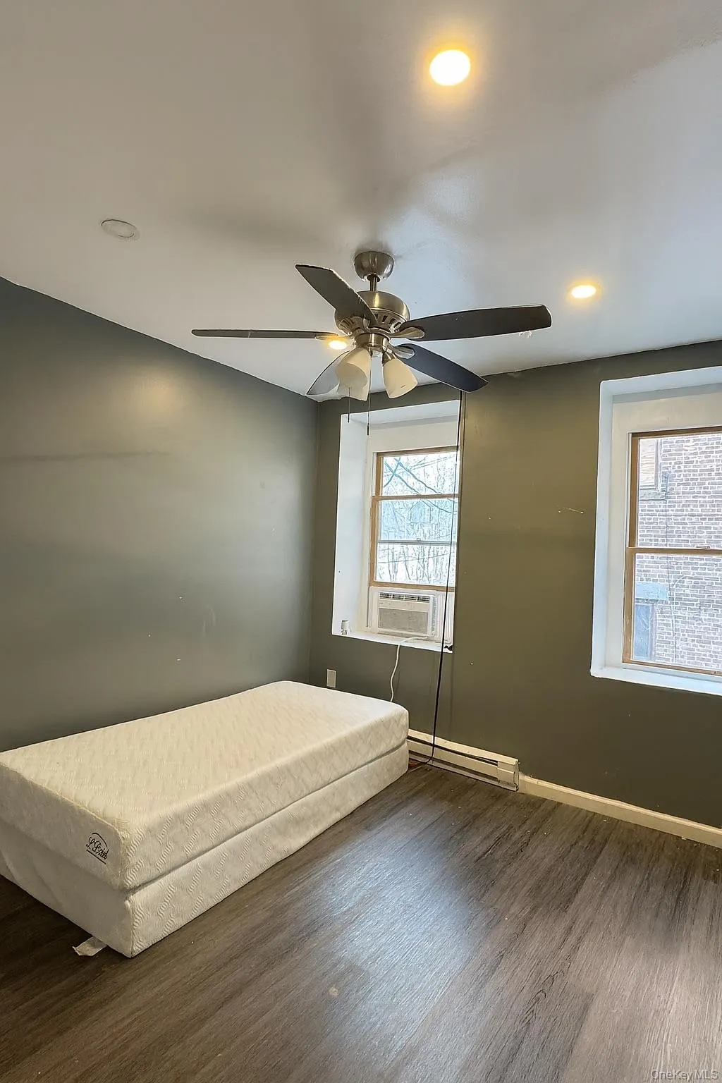 Bedroom with wood finished floors, a baseboard heating unit, recessed lighting, ceiling fan, and cooling unit Bedroom with wood finished floors, a baseboard heating unit, recessed lighting, ceiling fan, and cooling unit