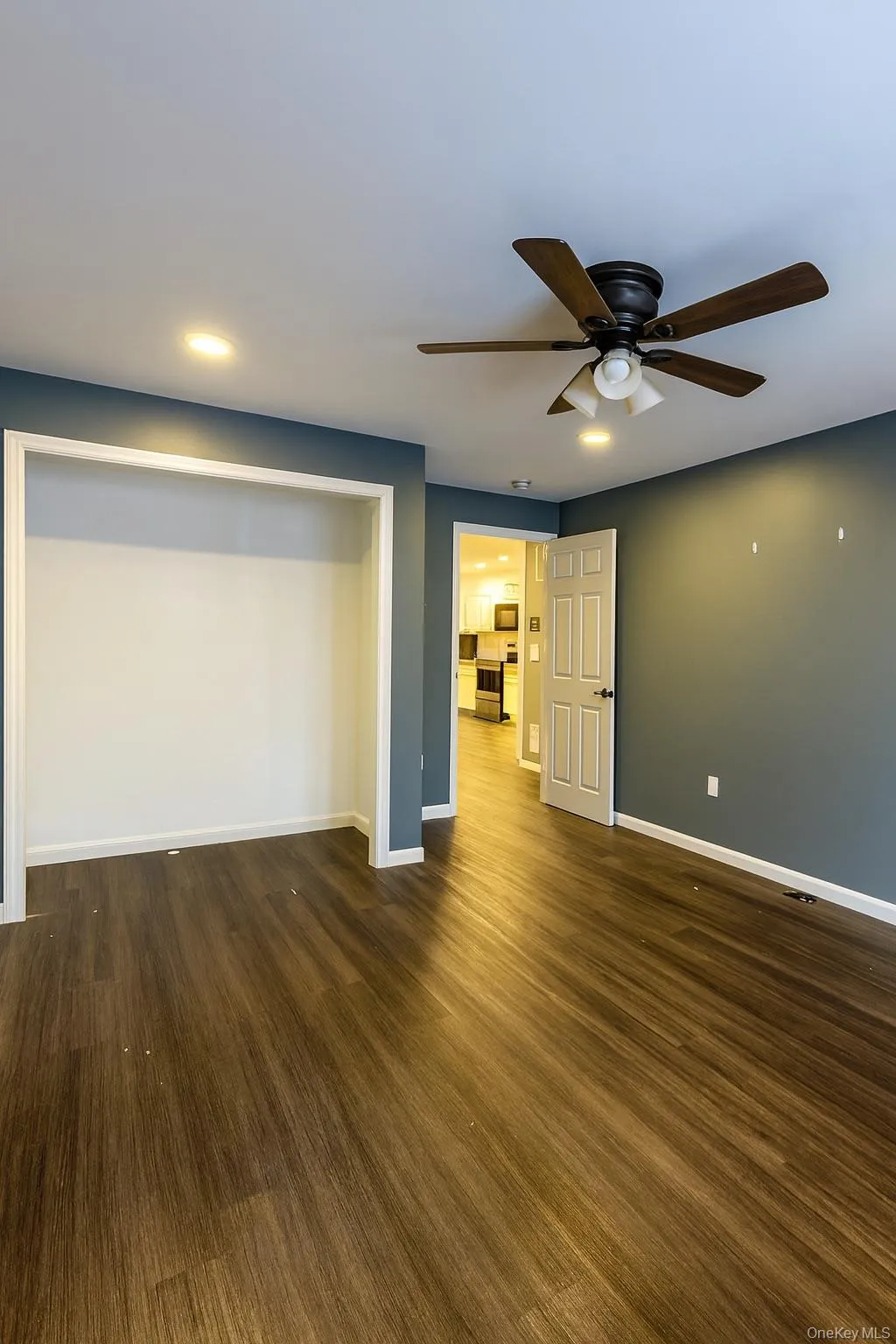 Unfurnished bedroom with a ceiling fan, dark wood-type flooring, and recessed lighting Unfurnished bedroom with a ceiling fan, dark wood-type flooring, and recessed lighting