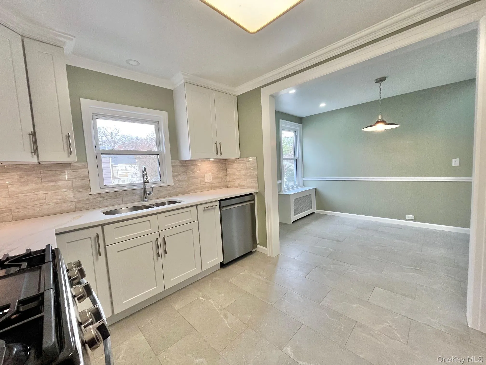 Kitchen featuring white cabinets, stainless steel appliances, light stone counters, tasteful backsplash, and crown molding Kitchen featuring white cabinets, stainless steel appliances, light stone counters, tasteful backsplash, and crown molding