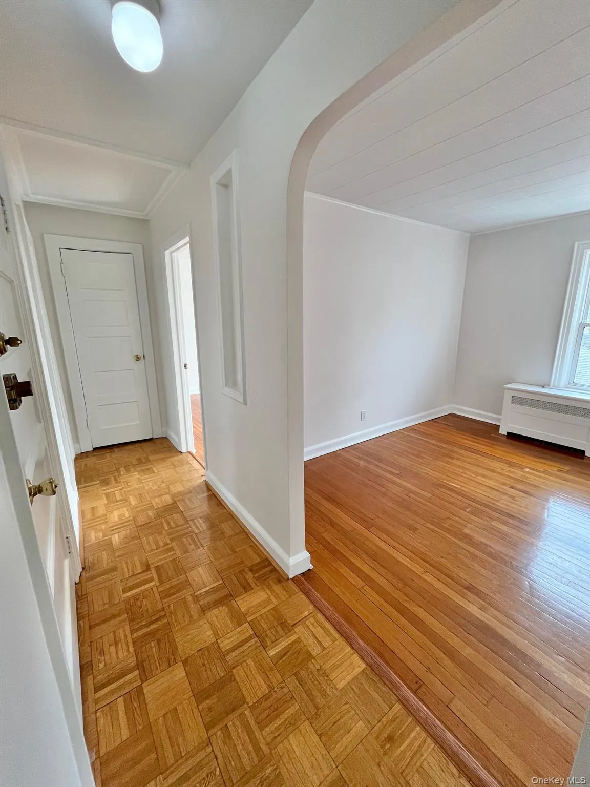 Hallway with arched walkways, parquet floors, and radiator heating unit Hallway with arched walkways, parquet floors, and radiator heating unit