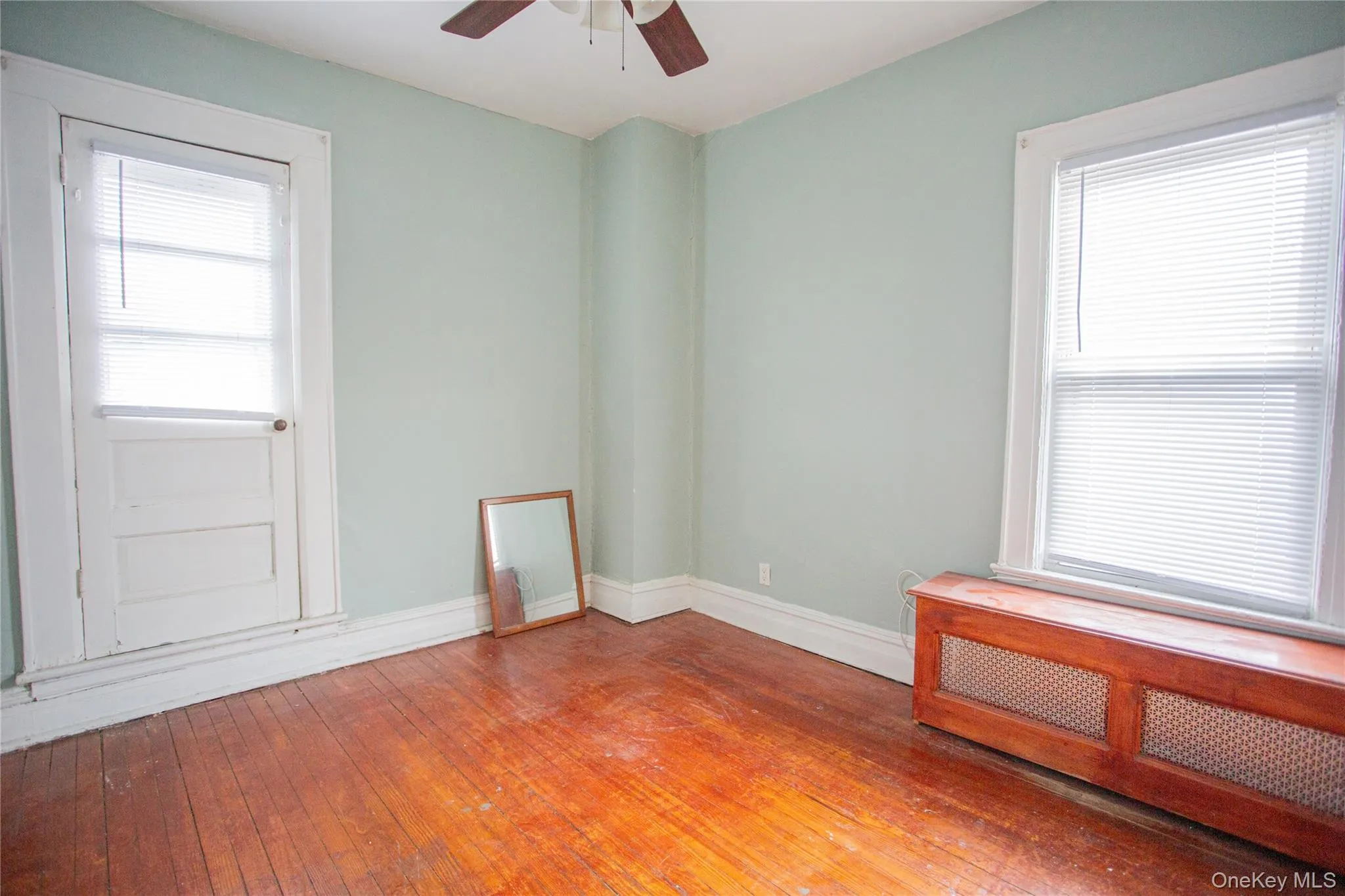 Unfurnished room with hardwood / wood-style flooring, radiator heating unit, and ceiling fan Unfurnished room with hardwood / wood-style flooring, radiator heating unit, and ceiling fan