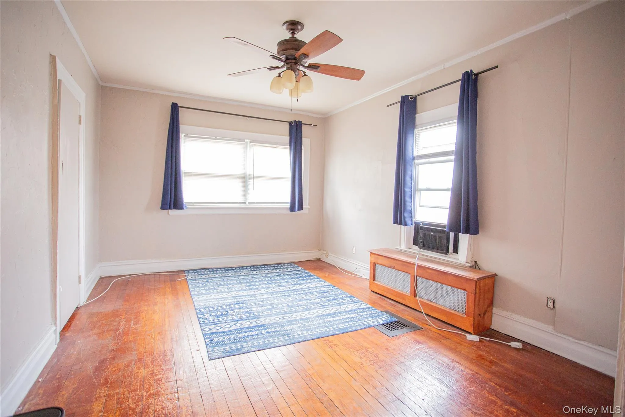 Spare room featuring hardwood / wood-style floors, crown molding, ceiling fan, and radiator heating unit Spare room featuring hardwood / wood-style floors, crown molding, ceiling fan, and radiator heating unit