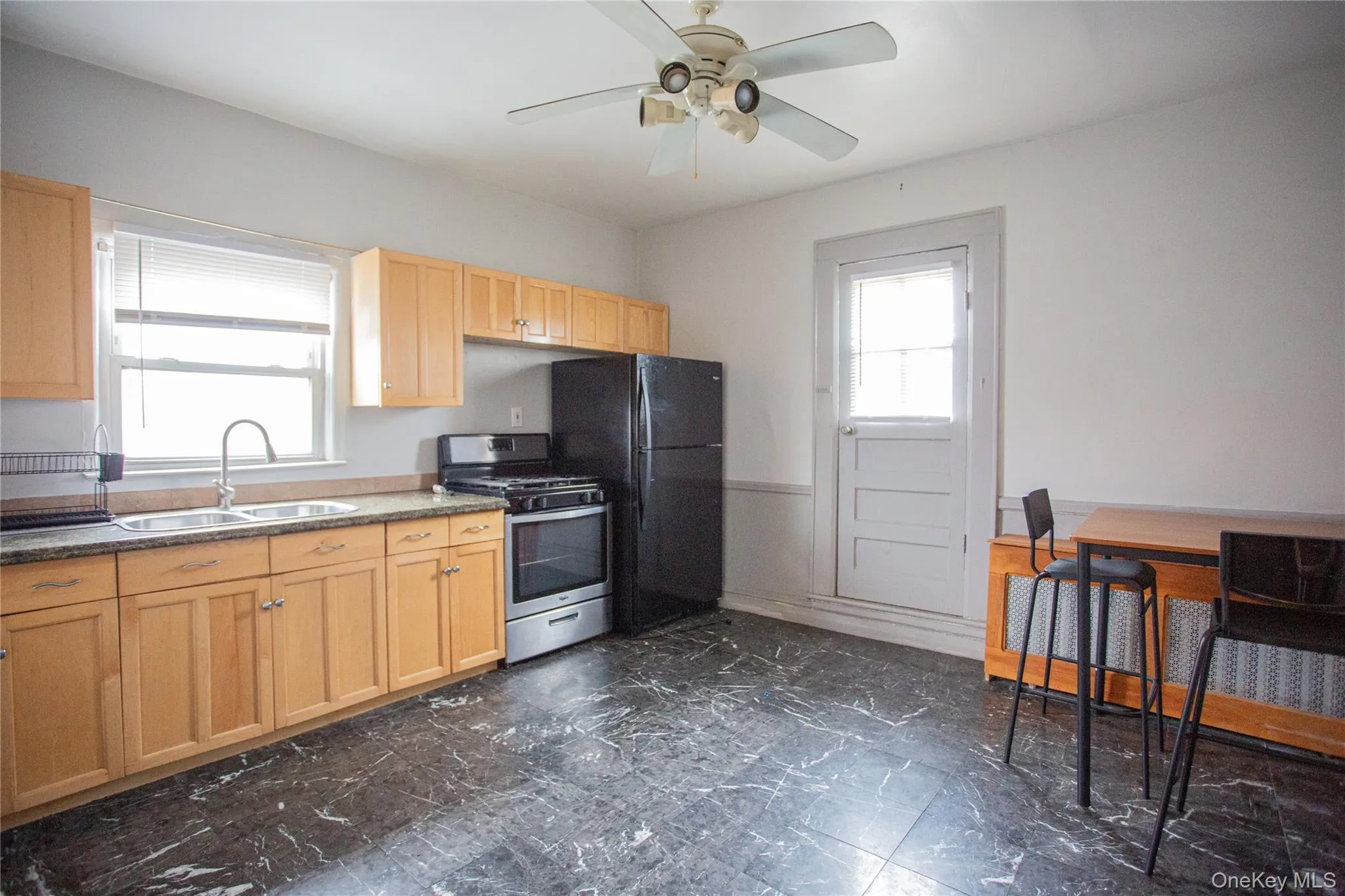 Kitchen with stainless steel range with gas stovetop, light brown cabinets, and a ceiling fan Kitchen with stainless steel range with gas stovetop, light brown cabinets, and a ceiling fan