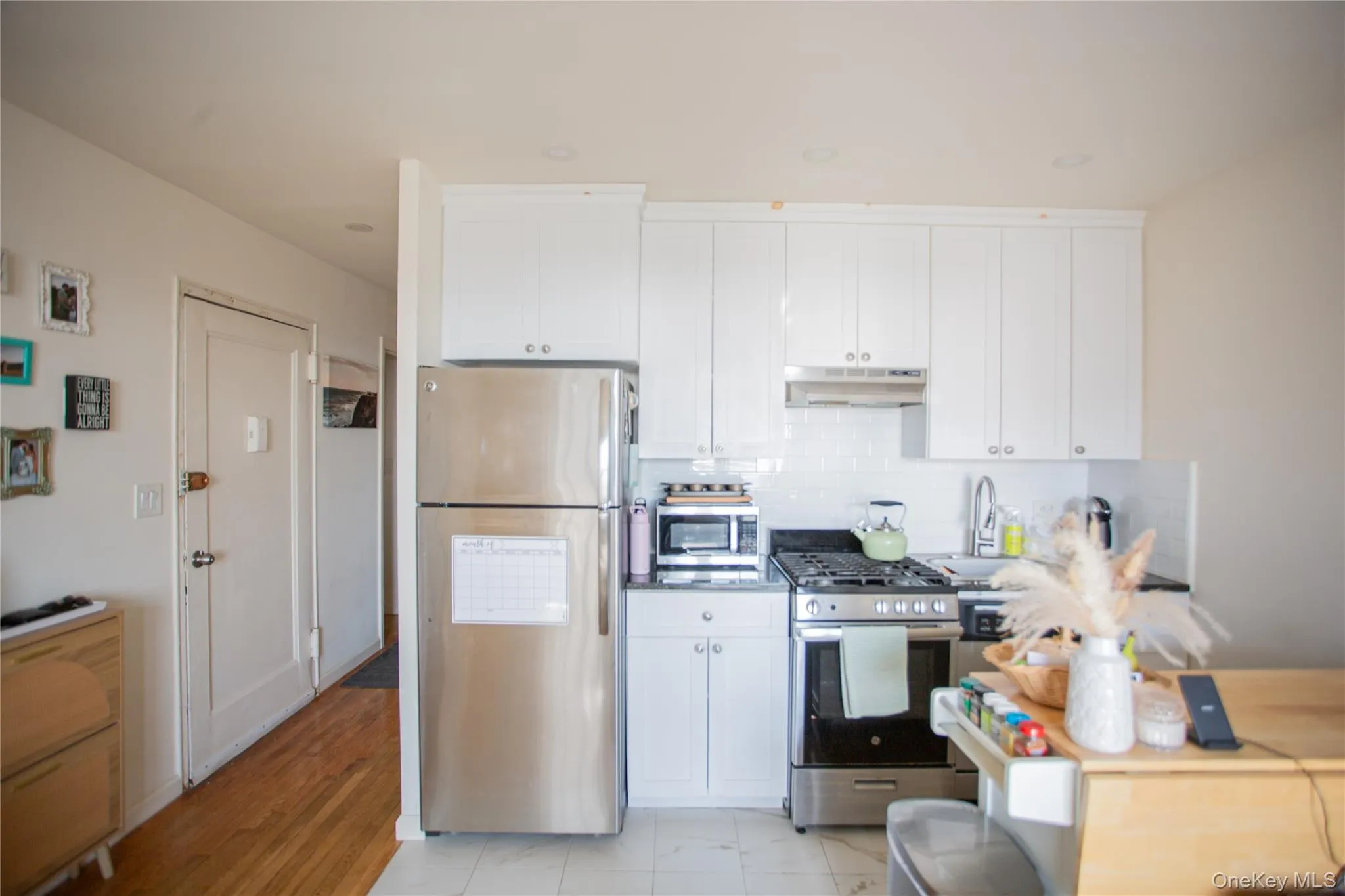 Kitchen with stainless steel appliances, white cabinetry, under cabinet range hood, and tasteful backsplash Kitchen with stainless steel appliances, white cabinetry, under cabinet range hood, and tasteful backsplash