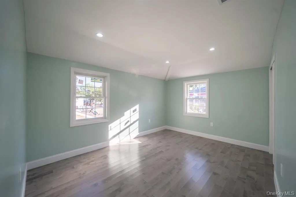 Unfurnished room with vaulted ceiling, dark wood-style floors, and recessed lighting Unfurnished room with vaulted ceiling, dark wood-style floors, and recessed lighting