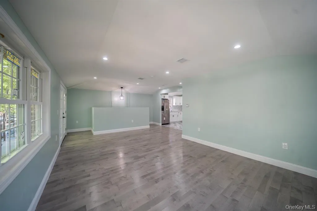 Unfurnished living room with dark wood-style flooring, recessed lighting, and vaulted ceiling Unfurnished living room with dark wood-style flooring, recessed lighting, and vaulted ceiling
