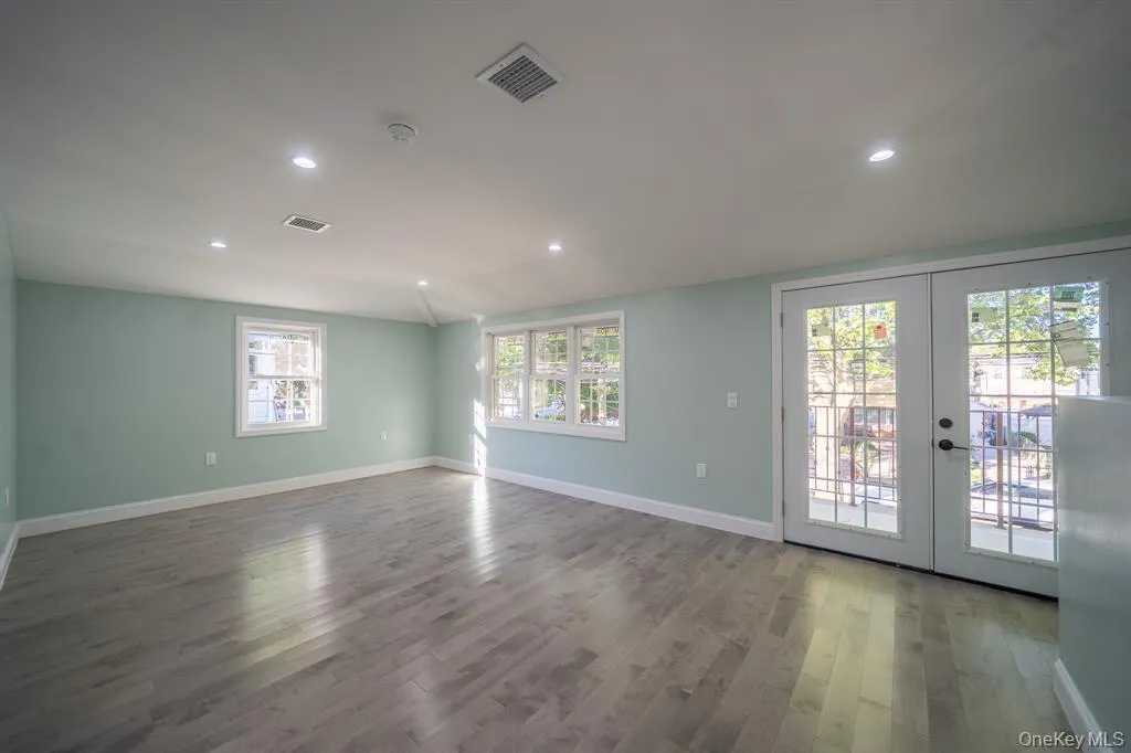 Empty room featuring french doors, wood finished floors, recessed lighting, and lofted ceiling Empty room featuring french doors, wood finished floors, recessed lighting, and lofted ceiling