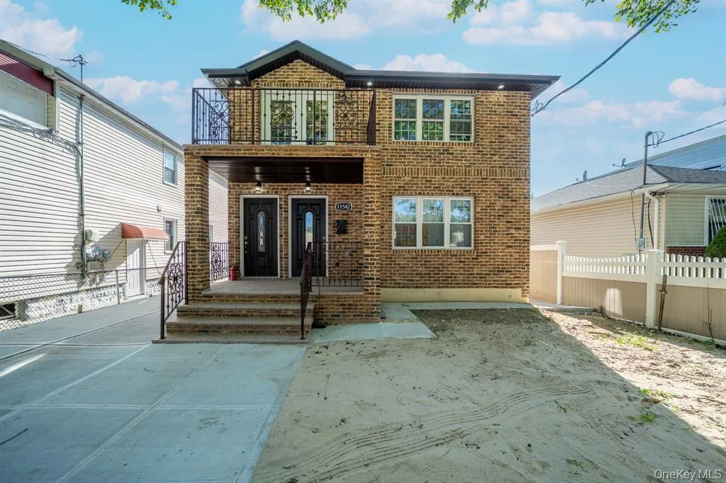 View of front facade with brick siding and a balcony View of front facade with brick siding and a balcony