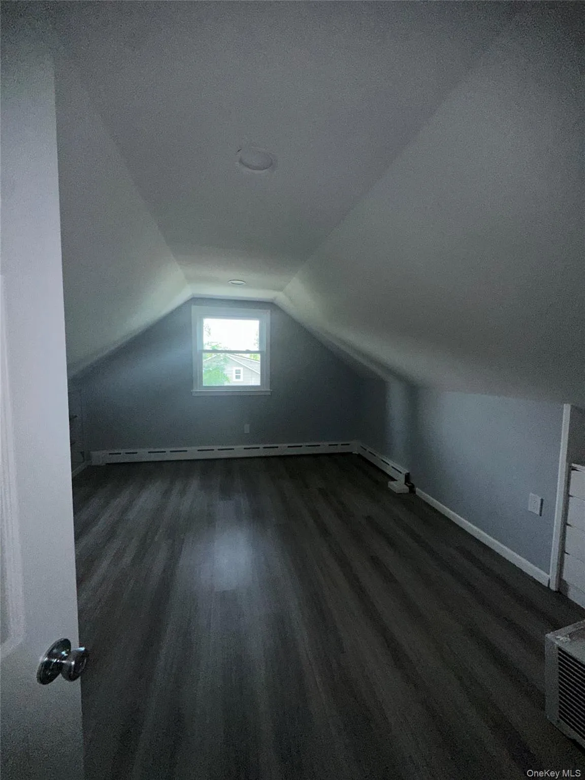 Bonus room featuring vaulted ceiling, dark wood-style floors, a textured ceiling, and a baseboard heating unit Bonus room featuring vaulted ceiling, dark wood-style floors, a textured ceiling, and a baseboard heating unit