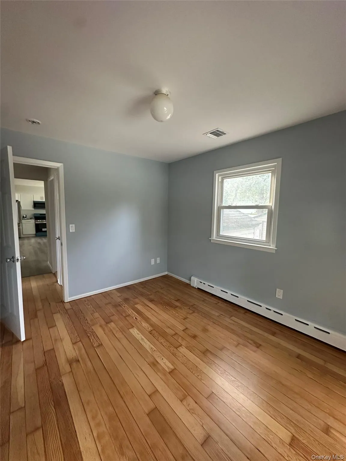 Spare room with baseboard heating and light wood-style floors Spare room with baseboard heating and light wood-style floors