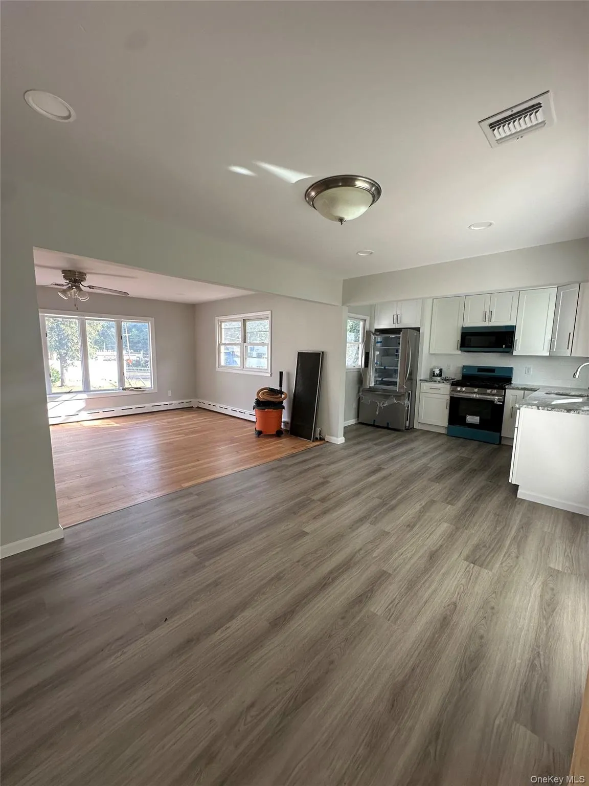 Unfurnished living room featuring healthy amount of natural light, light wood-style floors, ceiling fan, baseboard heating, and recessed lighting Unfurnished living room featuring healthy amount of natural light, light wood-style floors, ceiling fan, baseboard heating, and recessed lighting