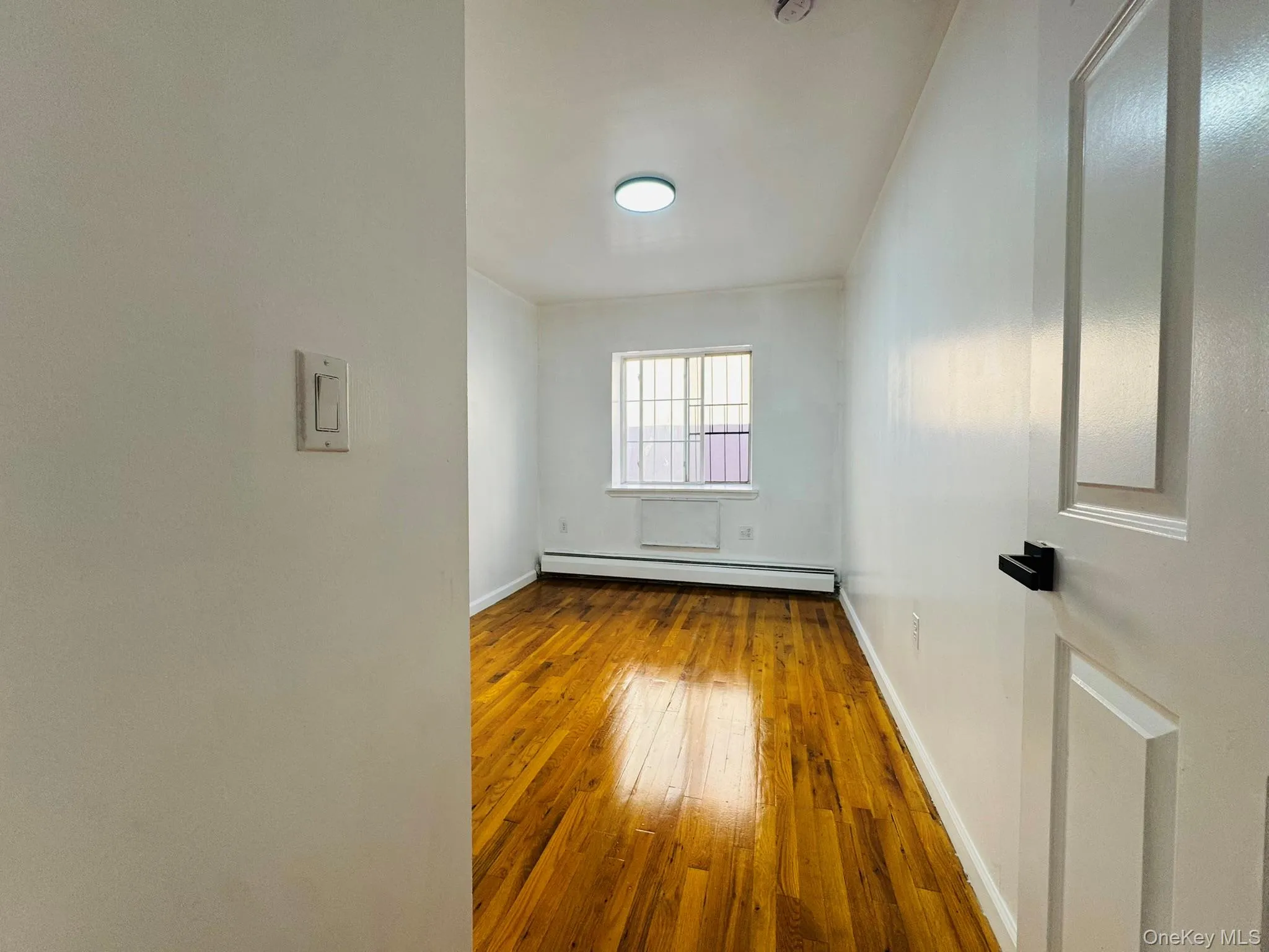Empty room featuring light wood-style flooring and baseboard heating Empty room featuring light wood-style flooring and baseboard heating