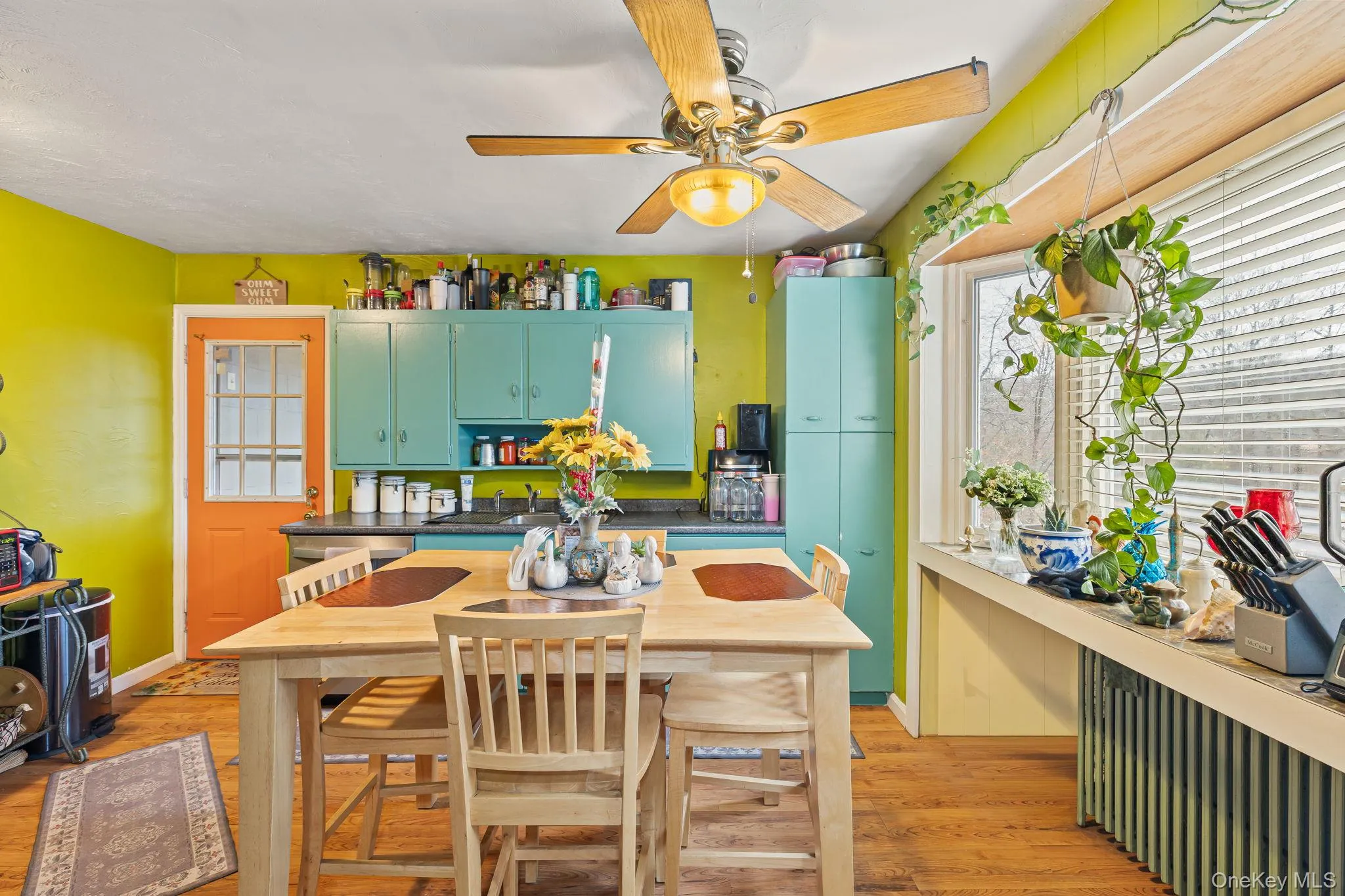Kitchen featuring dark countertops, radiator, light wood-style flooring, ceiling fan, and green cabinetry Kitchen featuring dark countertops, radiator, light wood-style flooring, ceiling fan, and green cabinetry