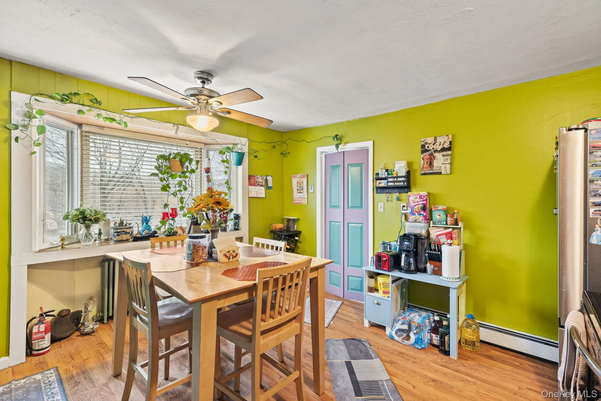 Dining space featuring baseboard heating, light wood-type flooring, and a ceiling fan Dining space featuring baseboard heating, light wood-type flooring, and a ceiling fan