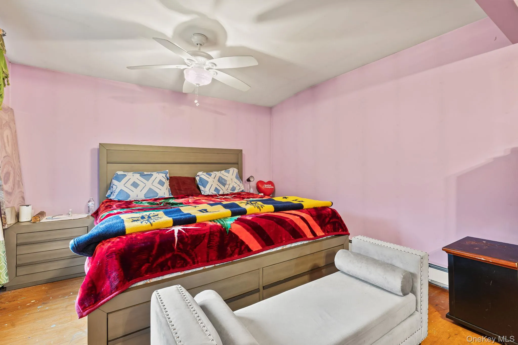 Bedroom with a ceiling fan, baseboard heating, and light wood finished floors Bedroom with a ceiling fan, baseboard heating, and light wood finished floors
