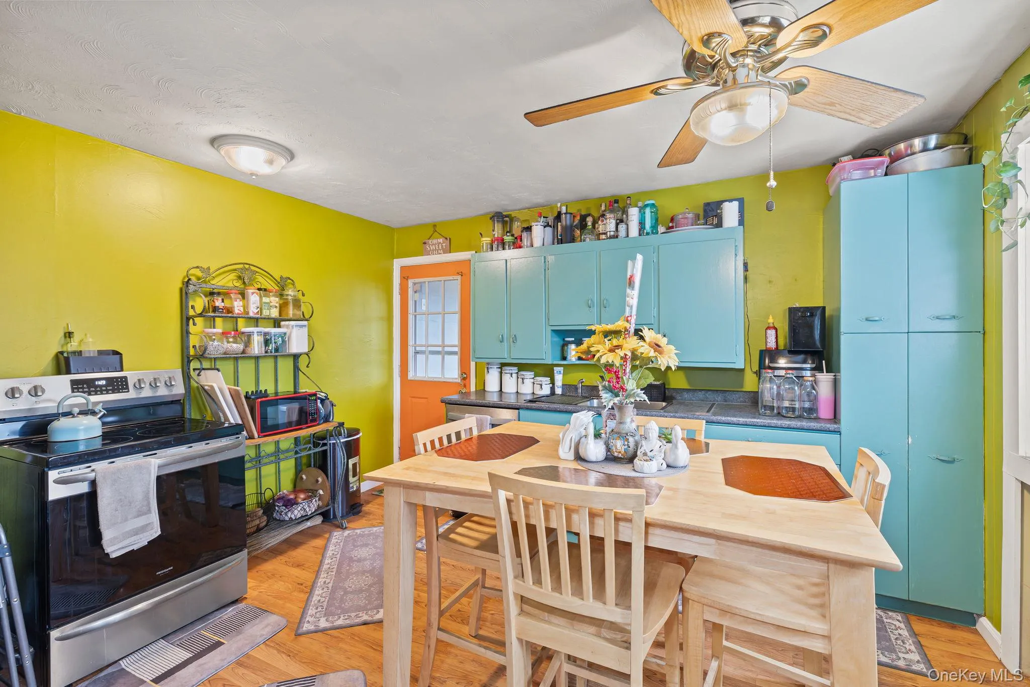 Kitchen with dark countertops, stainless steel electric stove, blue cabinetry, and light wood finished floors Kitchen with dark countertops, stainless steel electric stove, blue cabinetry, and light wood finished floors