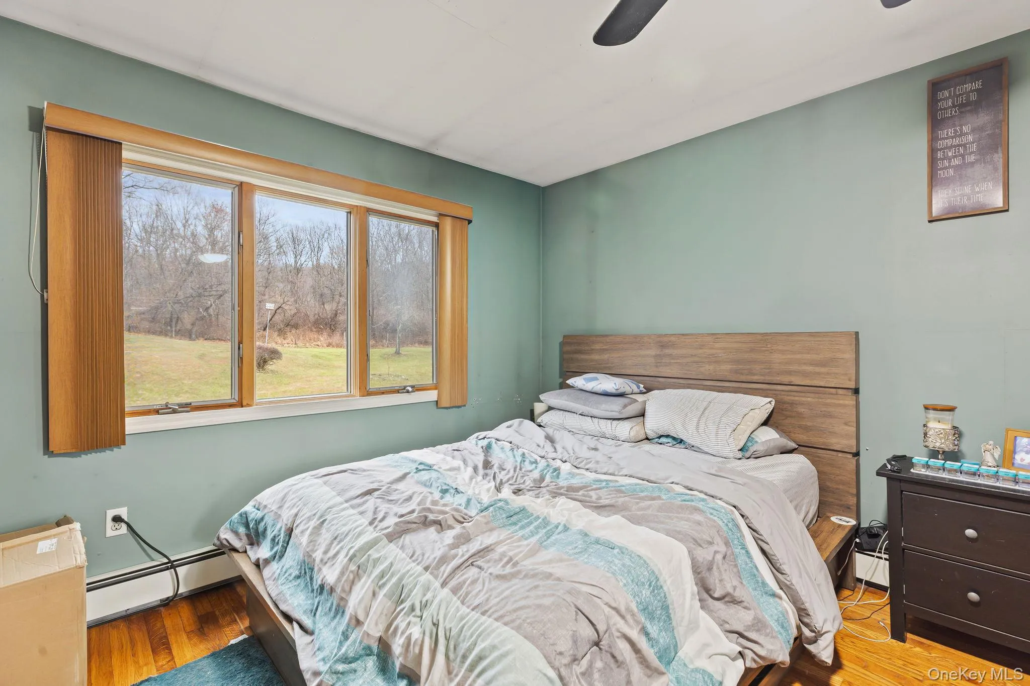 Bedroom featuring a baseboard radiator, wood finished floors, and a ceiling fan Bedroom featuring a baseboard radiator, wood finished floors, and a ceiling fan