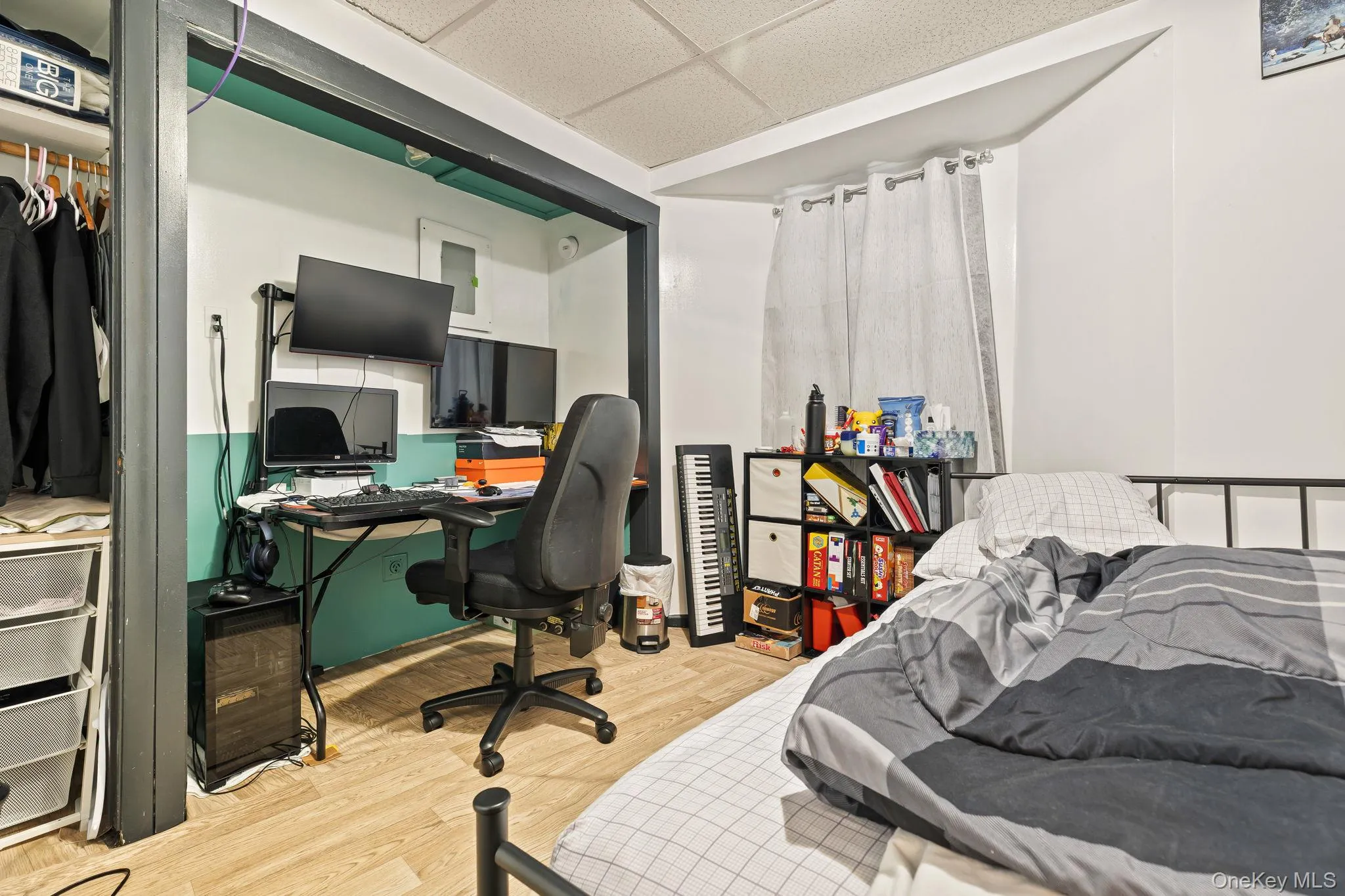 Bedroom featuring a drop ceiling, an office area, and light wood-style flooring Bedroom featuring a drop ceiling, an office area, and light wood-style flooring