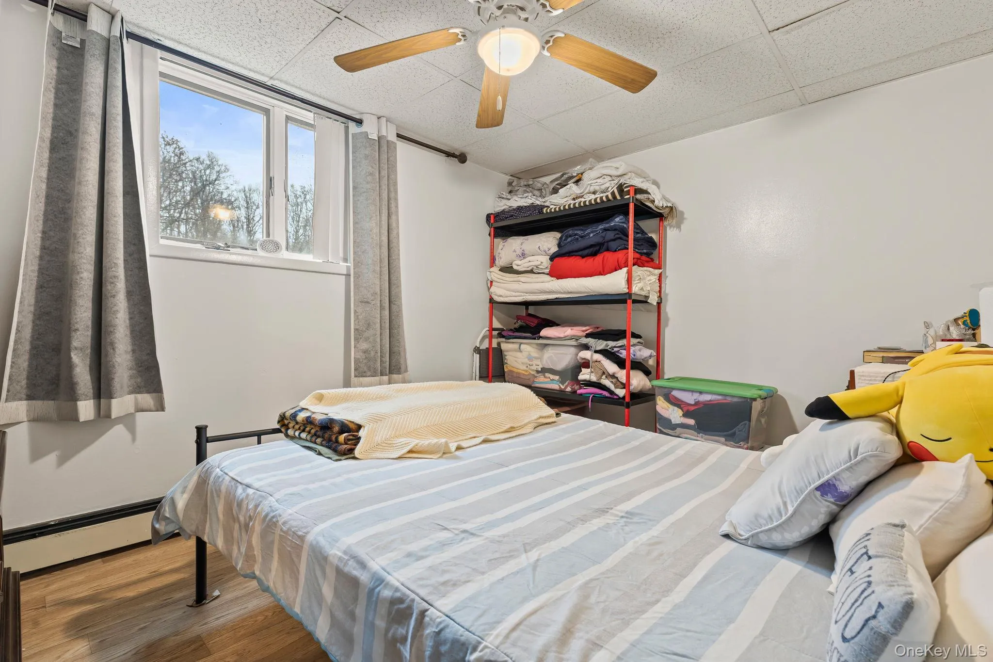 Bedroom featuring a baseboard heating unit, wood finished floors, a ceiling fan, and a paneled ceiling Bedroom featuring a baseboard heating unit, wood finished floors, a ceiling fan, and a paneled ceiling