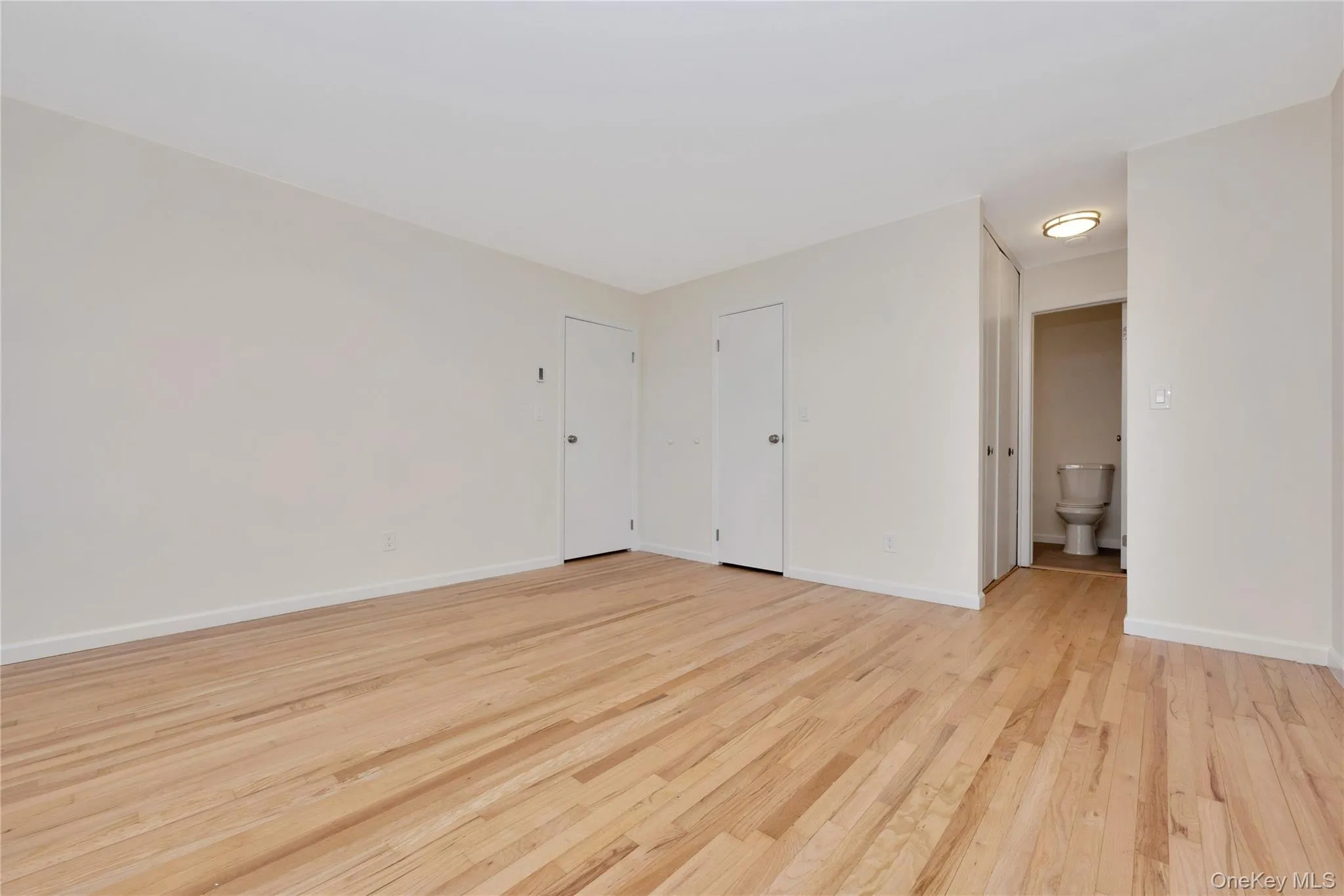 Empty room with light wood finished floors and baseboards Empty room with light wood finished floors and baseboards