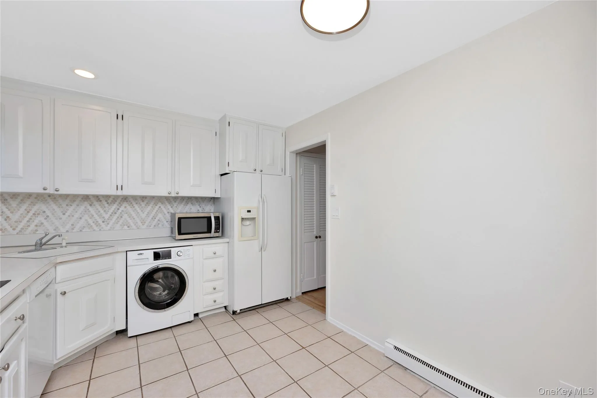 Washroom featuring washer / clothes dryer, a baseboard heating unit, and light tile patterned flooring Washroom featuring washer / clothes dryer, a baseboard heating unit, and light tile patterned flooring