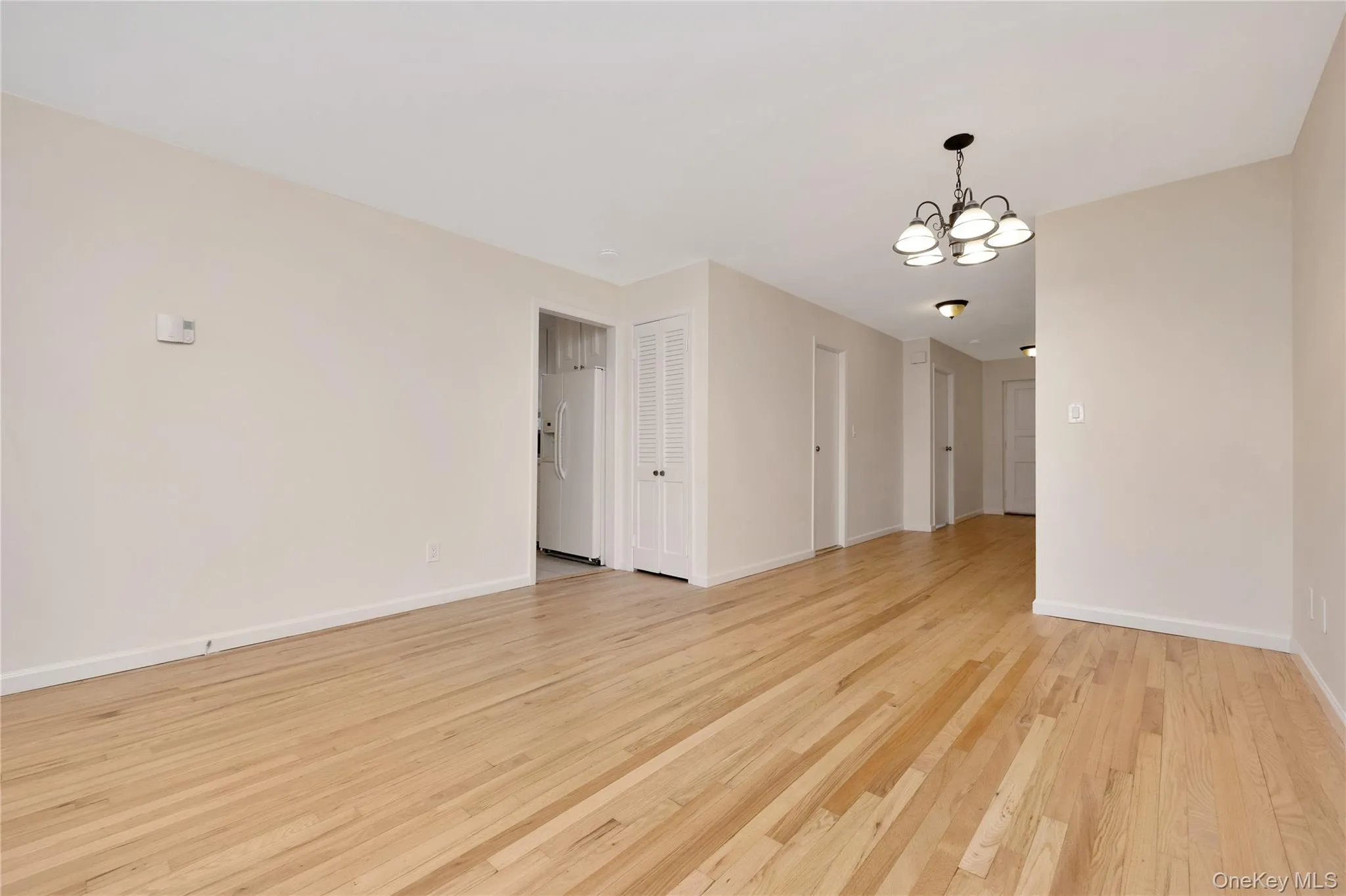Empty room featuring a chandelier and light wood finished floors Empty room featuring a chandelier and light wood finished floors
