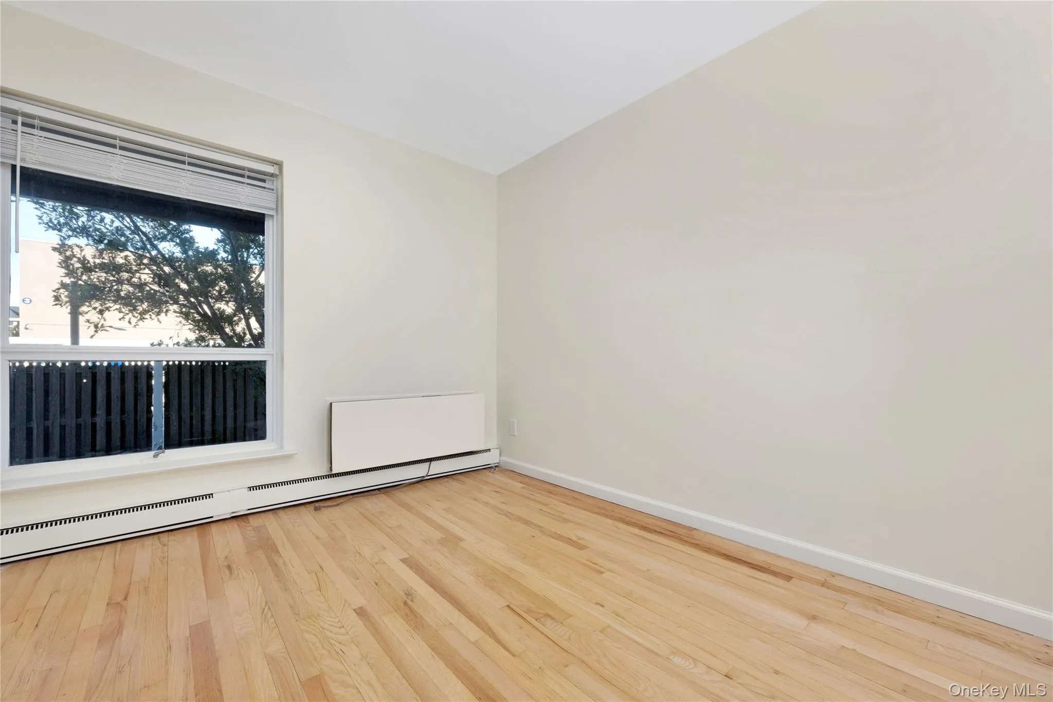 Unfurnished room with hardwood / wood-style flooring and a baseboard heating unit Unfurnished room with hardwood / wood-style flooring and a baseboard heating unit