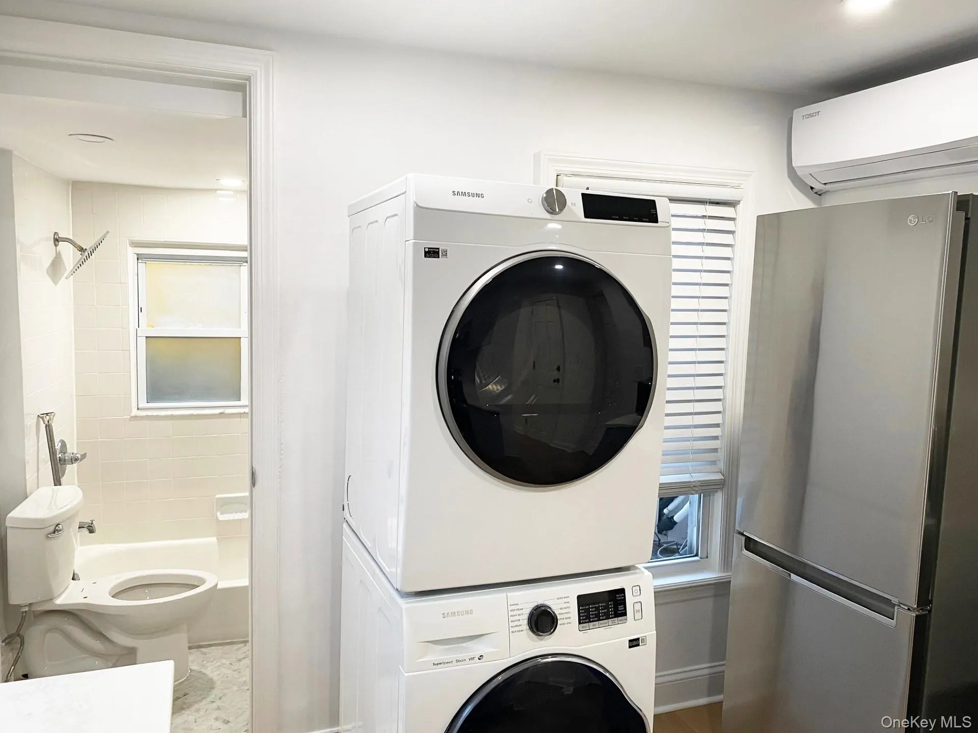 Washroom with a wall unit AC, estacked washer and dryer, and recessed lighting Washroom with a wall unit AC, estacked washer and dryer, and recessed lighting