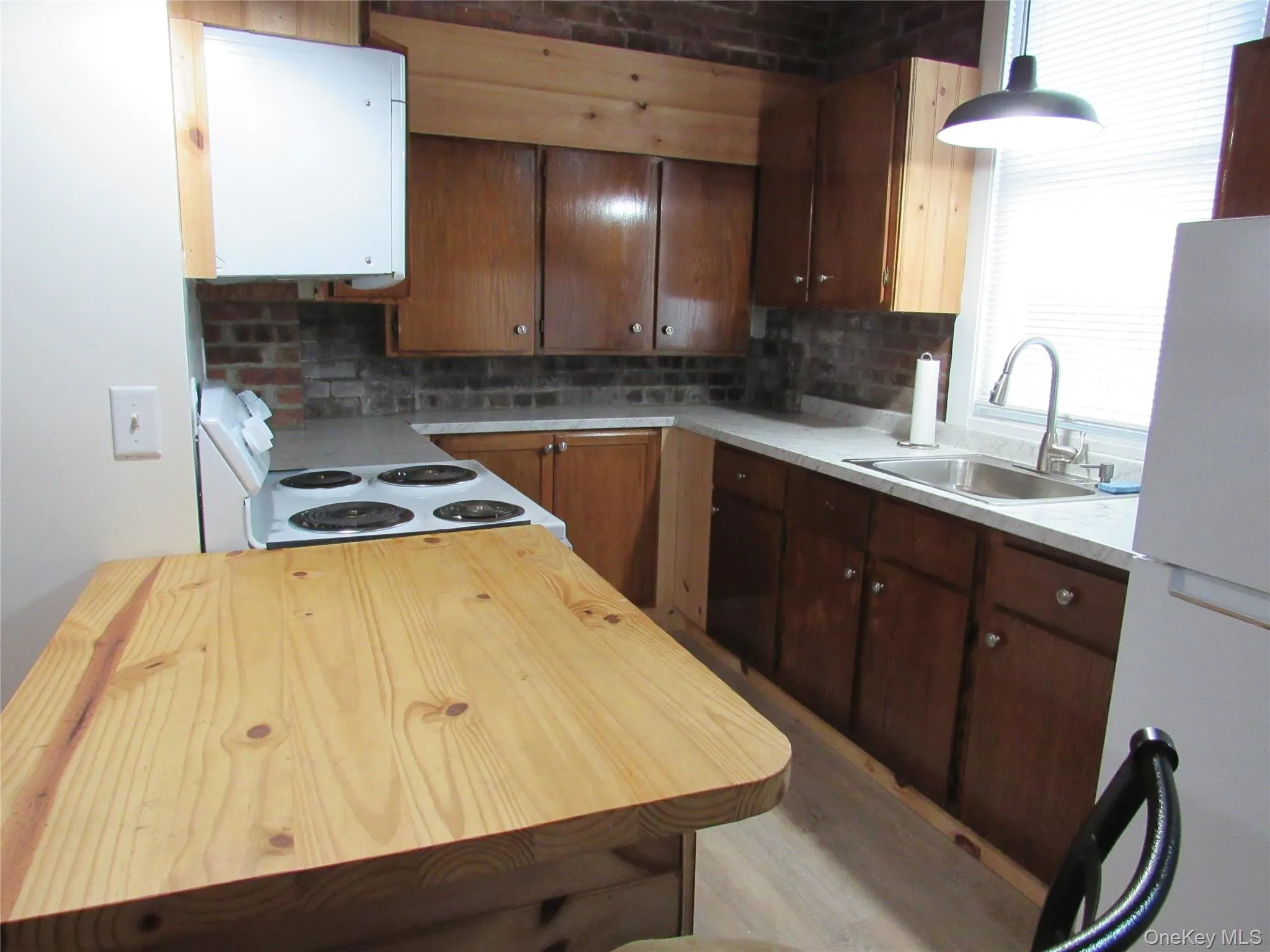 Kitchen with white appliances, butcher block counters, backsplash, and light wood-type flooring Kitchen with white appliances, butcher block counters, backsplash, and light wood-type flooring