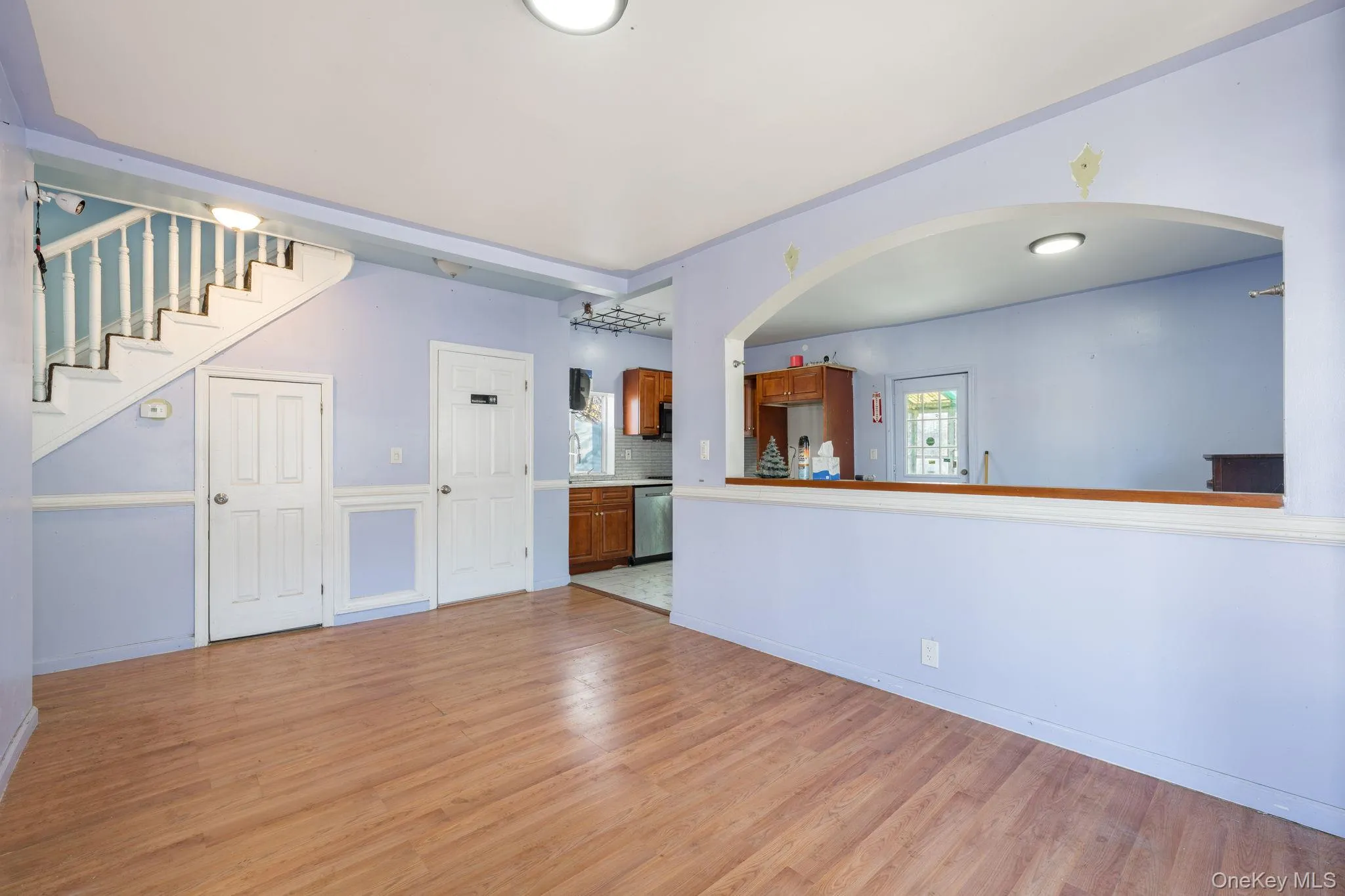 Unfurnished living room with light wood-style flooring, stairs, and arched walkways Unfurnished living room with light wood-style flooring, stairs, and arched walkways